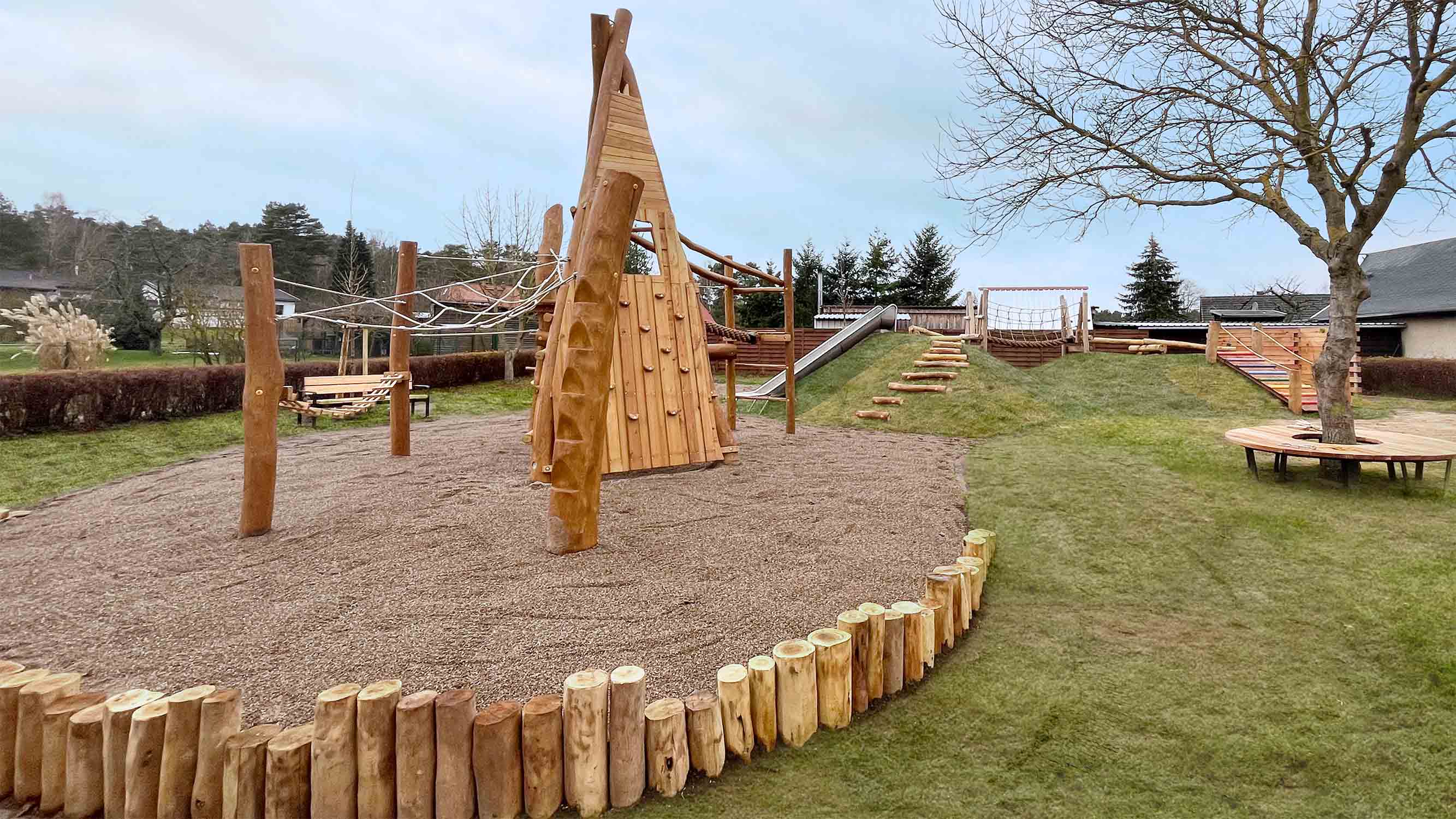 Die Kletterkombination stellt eins der Spielelemente für etwas größere Kinder dar. Der leichte Höhenunterschied im Gelände wird hier durch Robinienpalisaden aufgefangen, die auch zum Balancieren genutzt werden können.